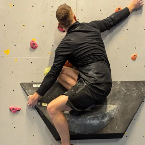 Image of a climber crouched down on a volume, starting a route.