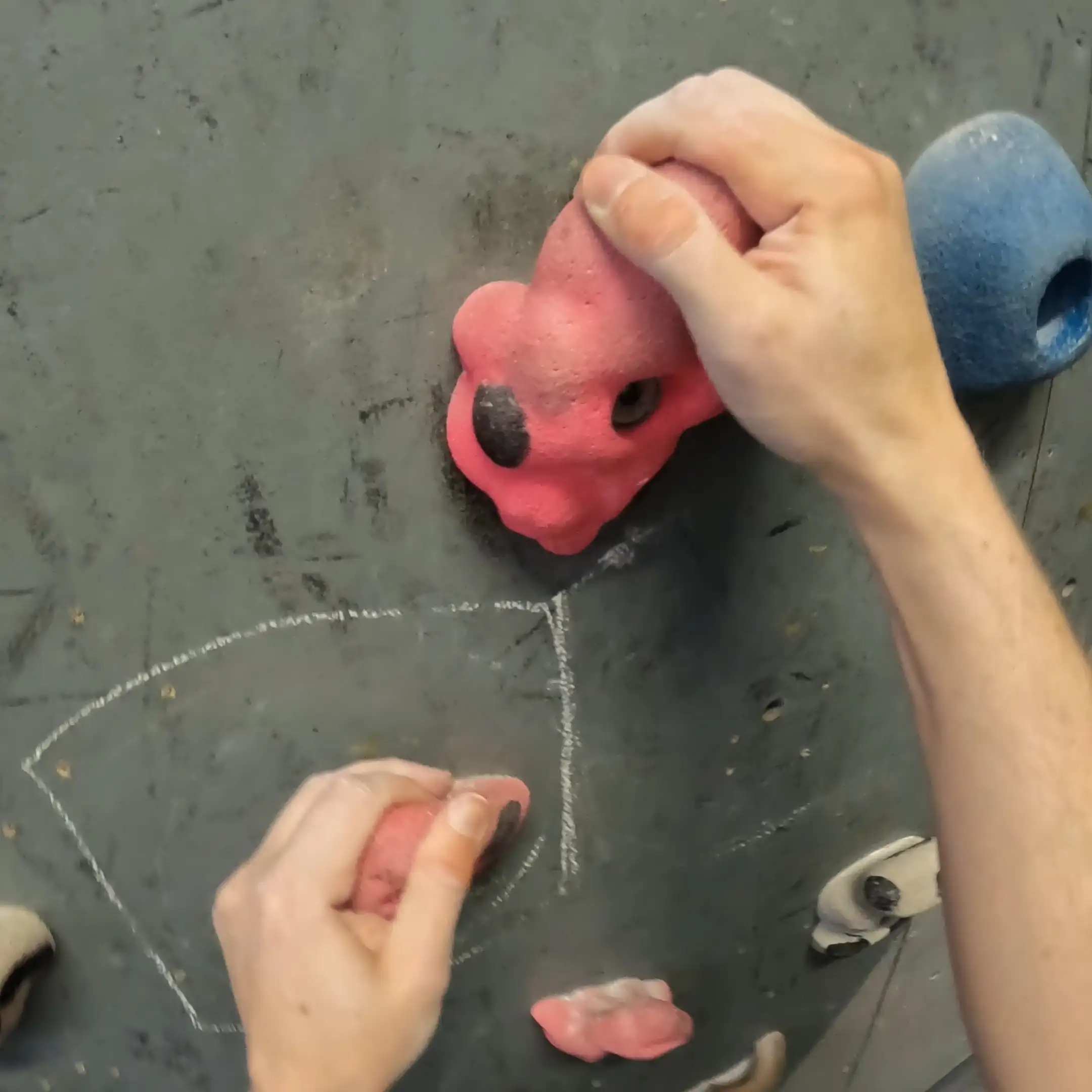 Two pink jug holds shows a person gripping onto them with their hands.