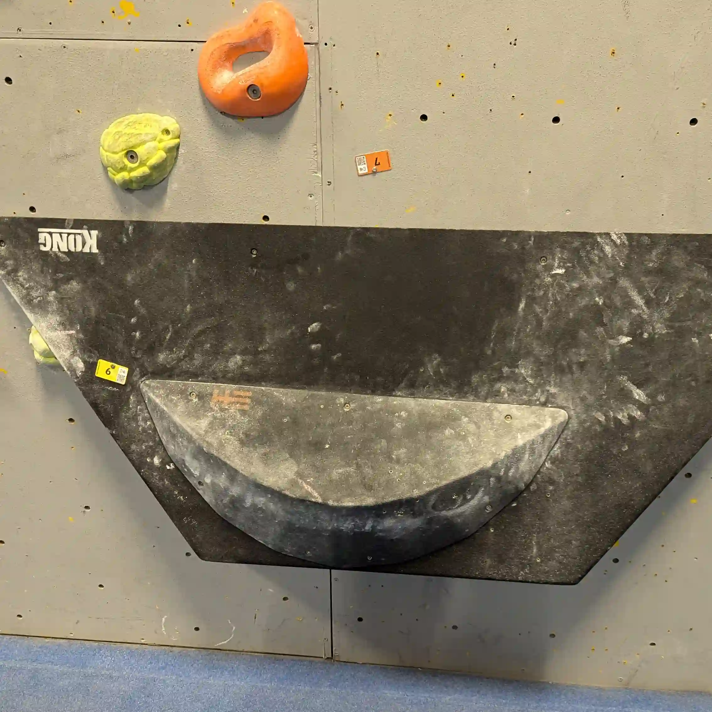 Shows the climber on the bouldering wall attempting to position his toe for the the toe hook.