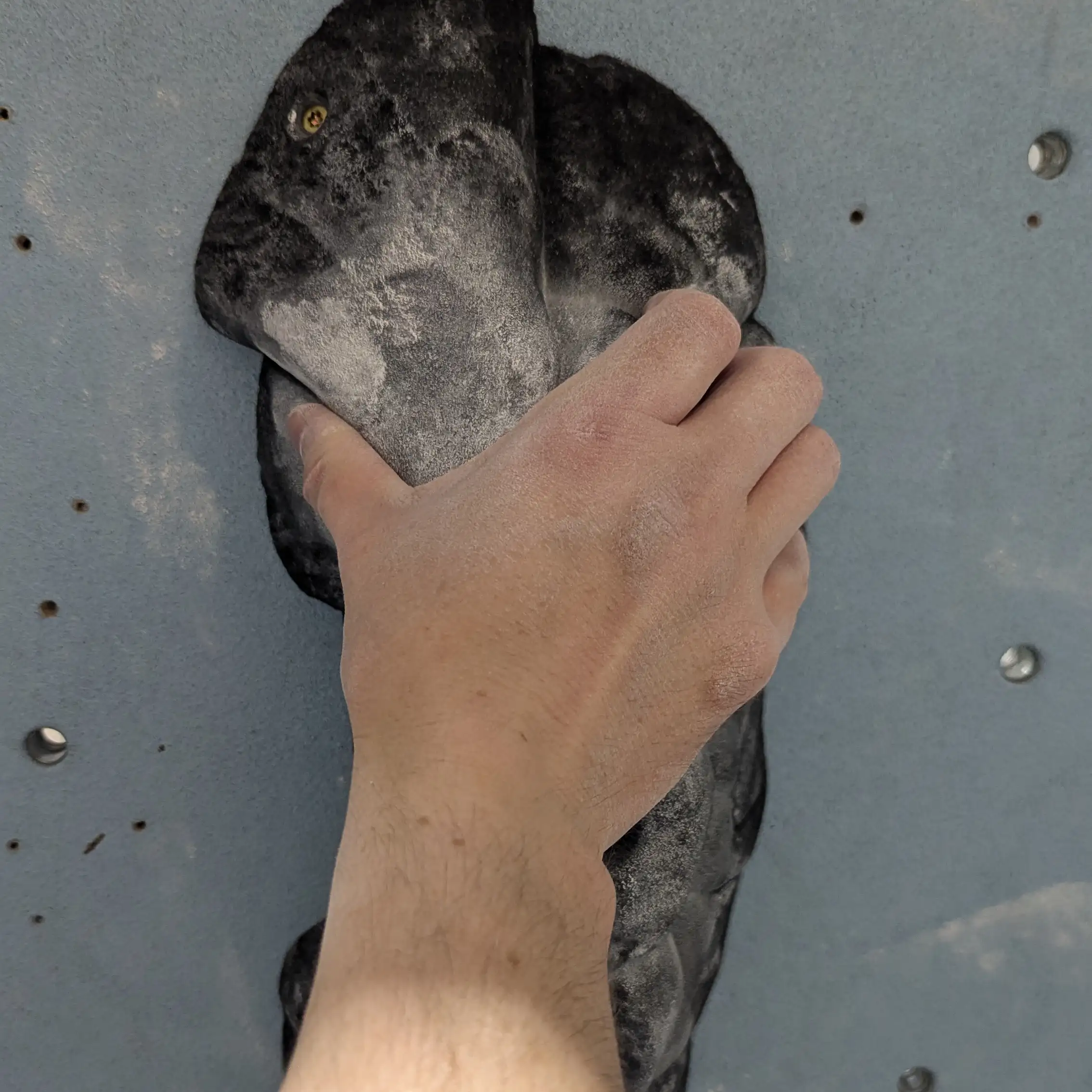 A hand pinching the large black pinch hold near the top.