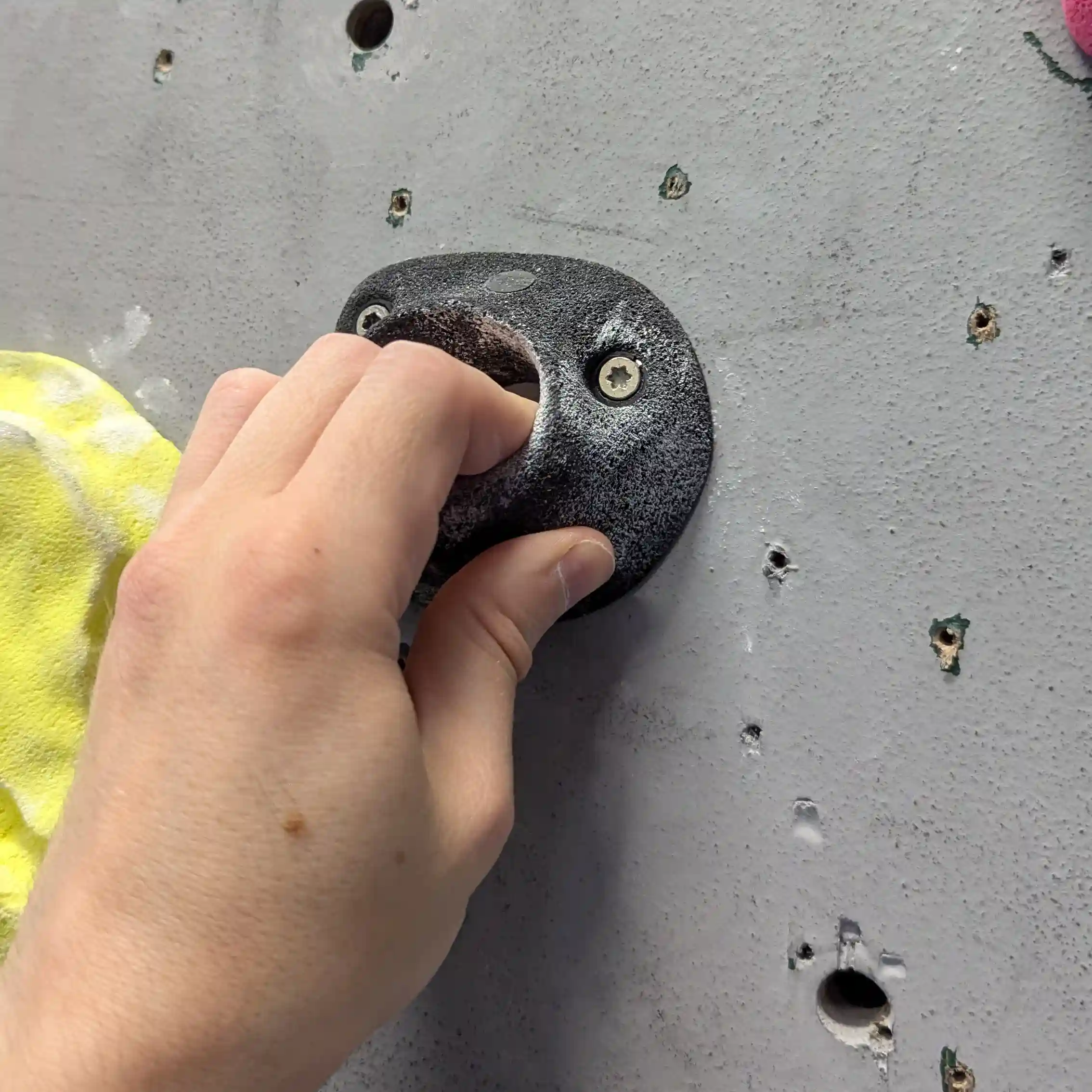 Shows the climber using 3 fingers and a thumb to grip tightely onto the small black pocket hold.