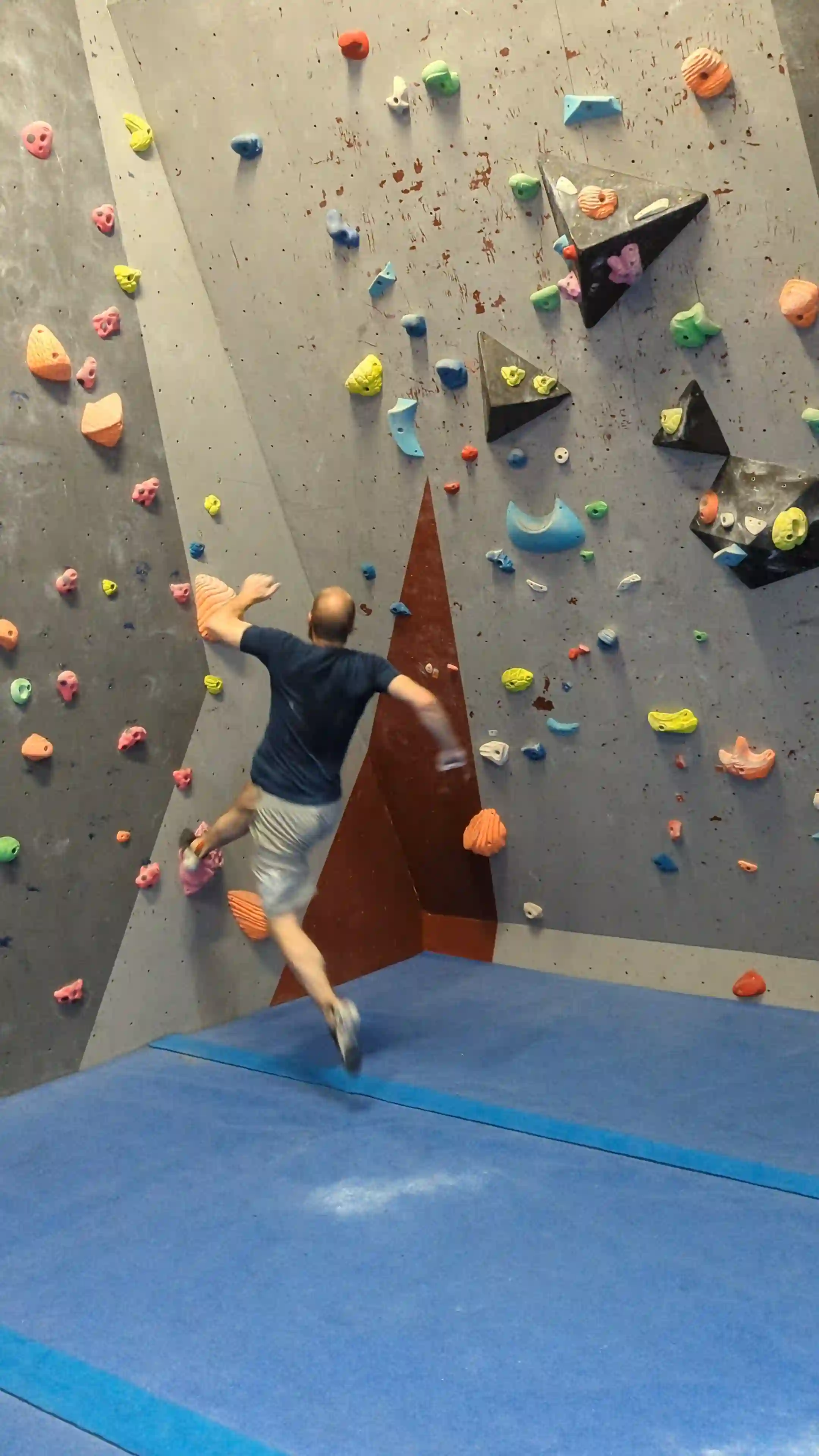 Shows the climber running up to a large foothold at the bottom of the climbing wall.